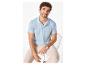 Homme en polo bleu clair et pantalon beige, assis sur une chaise en métal.