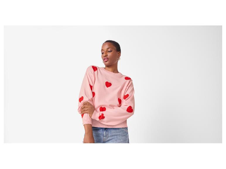 Femme en pull rose à cœurs rouges et jean