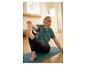 Femme en t-shirt vert et legging noir s'étirant sur un tapis de yoga.