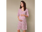 Une femme enceinte portant une robe à fleurs rose.