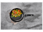 Une poêle avec des légumes sautés sur une surface en béton.