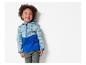 Un jeune enfant souriant porte une veste softshell bleu turquoise et bleu sur le thème du voyage.