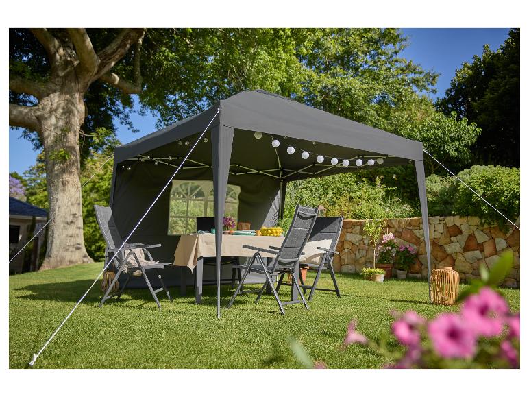 Tonnelle grise avec mobilier et décorations installés dans un jardin.