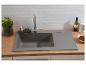 Évier gris avec robinet, brosse à vaisselle, persil et accessoires de cuisine sur plan de travail en bois.