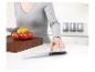 Une femme saisit un couteau de cuisine sur un comptoir avec des légumes et une planche à découper.