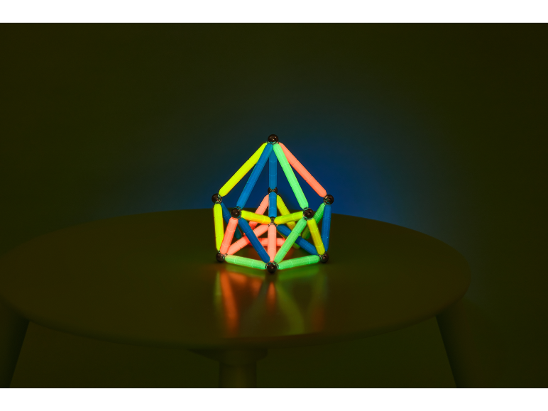 Construction géométrique lumineuse sur une table sur fond sombre.