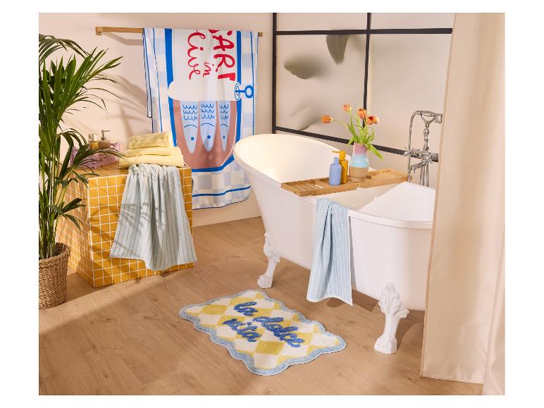 Drap de bain LIVARNO® avec motif de poissons suspendu à un porte-serviette en bois.