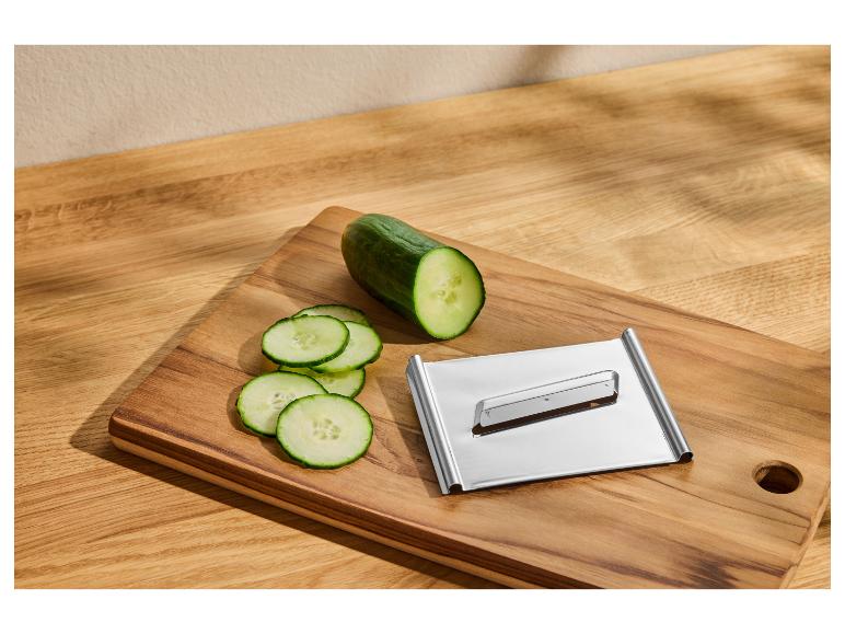 Concombre tranché et mandoline de cuisine sur une planche à découper en bois.