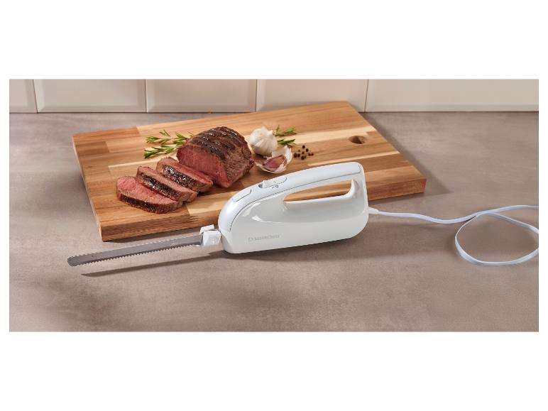 Un couteau électrique blanc à côté d'un rôti de bœuf tranché sur une planche à découper en bois.