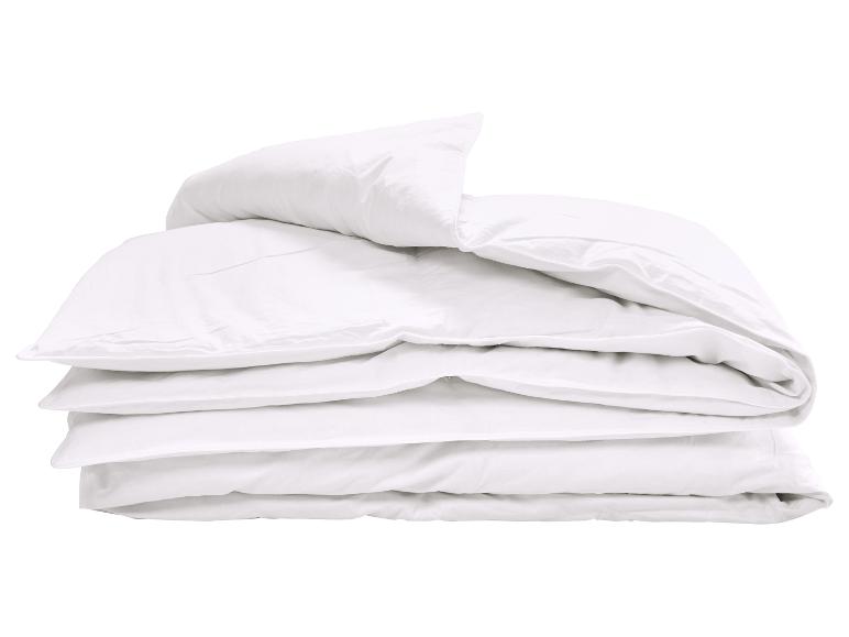 Pile de couettes et oreillers blancs pliés.