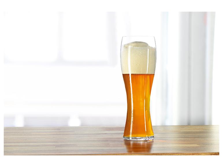 Un verre de bière blonde sur une table en bois.