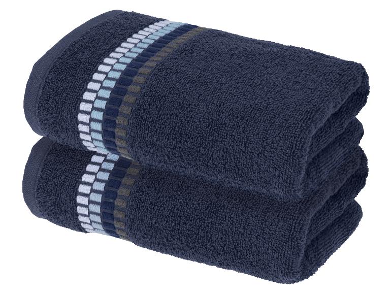Deux serviettes de bain bleu foncé pliées avec un motif rayé décoratif