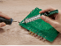 Fer à souder et pompe à dessouder sur carte de circuit imprimé verte sur table en bois.