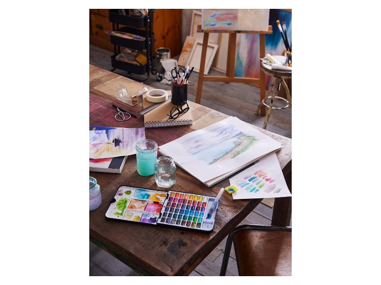 Ensemble d'aquarelle, pinceau, eau et papier sur une table en bois dans un studio d'art.