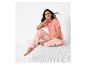 Femme portant un pantalon de pyjama rayé rose et un t-shirt rose.