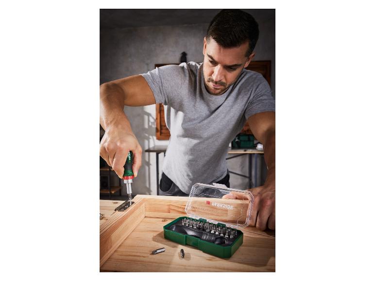 Un homme utilise un tournevis avec un jeu d'embouts Parkside pour assembler un cadre en bois.