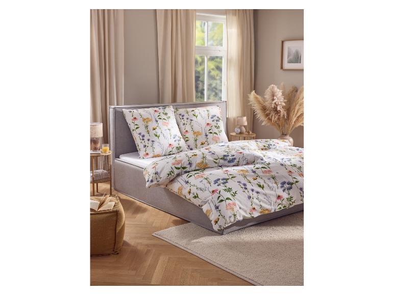 Chambre avec un lit doté d'une housse de couette et d'oreillers fleuris, une table d'appoint et de l'herbe de la pampa.