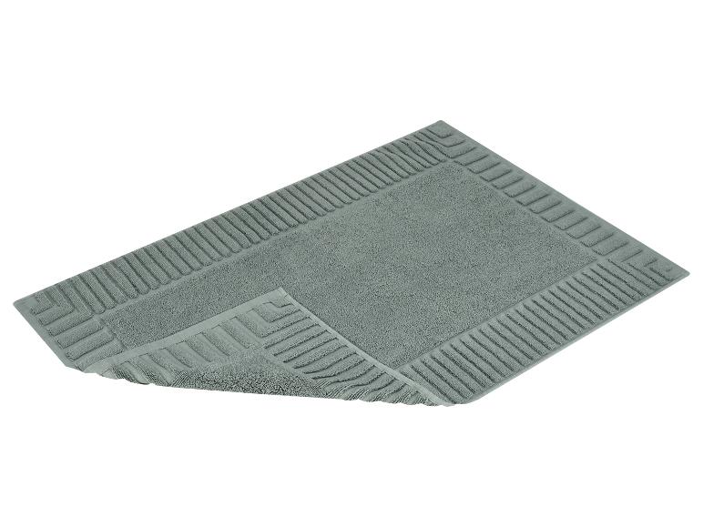 Tapis de bain gris avec un motif rayé en relief sur le pourtour.