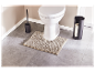 Accessoires de salle de bain modernes : brosse de toilette, porte-papier toilette et tapis de bain.