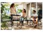 Trois personnes se détendent sur une terrasse avec des chaises noires, une table noire et un tapis en jute.