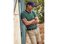 Un homme portant un polo vert, un short beige à imprimé cheval et une casquette bleue.