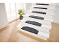 Escalier blanc avec tapis antidérapants gris, plante verte près de la fenêtre.
