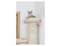 Un chat tigré gris se repose sur un lit moelleux au sommet d'un poteau à griffer, contre un mur blanc.
