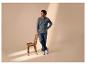 Homme en jean et t-shirt à manches longues debout à côté d'une chaise en bois.