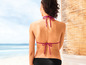 Une femme en bikini rose regardant l'océan.