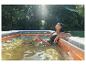 Femme se relaxant dans une piscine gonflable en extérieur sous le soleil.
