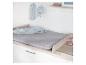 Table à langer avec matelas gris, couverture bleue, bavoir et peluche.