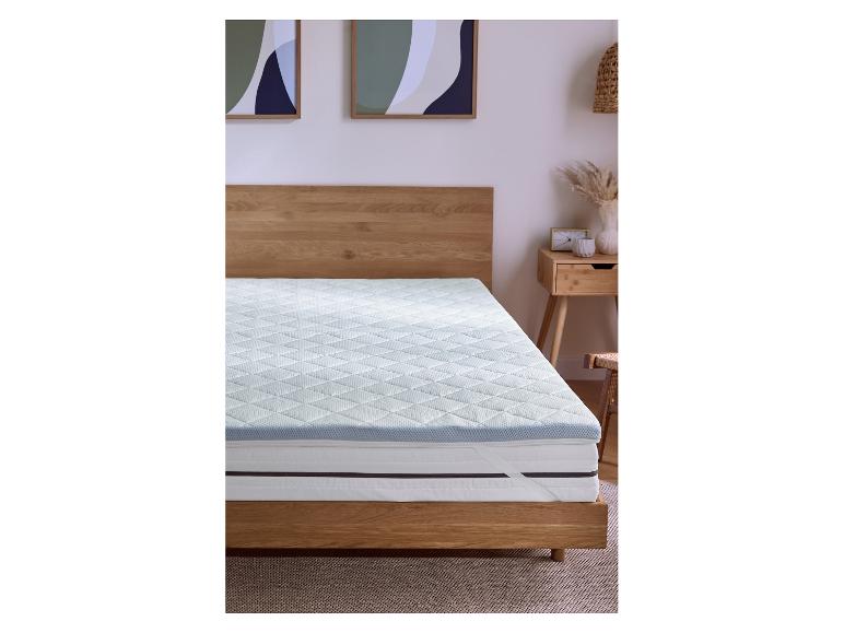 Matelas avec surmatelas dans une chambre avec lit en bois et table de chevet.