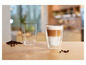 Un verre de cappuccino et un verre vide sur une table en bois avec des grains de café.
