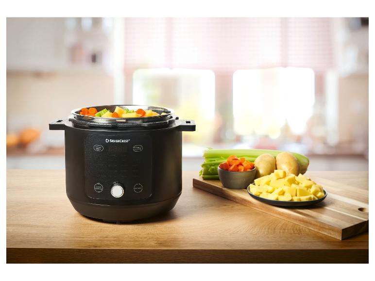 Autocuiseur électrique avec légumes coupés en dés sur une table en bois.
