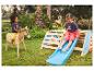 Deux enfants jouent sur un cheval à bascule en bois et un toboggan dans le jardin.