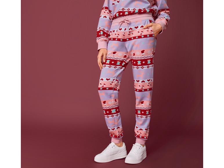 Femme portant un pantalon de survêtement à motif de Noël et des baskets blanches.