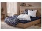 Chambre avec un lit en bois, une parure de lit à motif hivernal et une couette blanche.