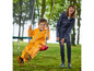 Un enfant en combinaison de pluie orange se balance sur une balançoire.