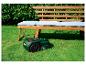 Robot tondeuse Parkside devant un banc en bois avec coussins dans un jardin.