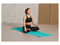 Une femme en tenue de sport assise sur un tapis de yoga bleu de Decathlon.