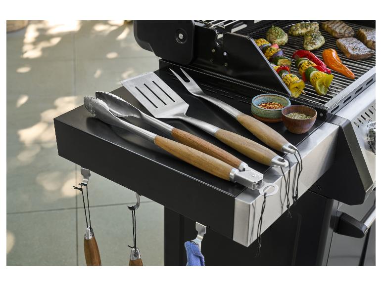 Barbecue avec ustensiles de cuisine, épices et brochettes de viande et légumes grillés.