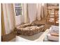 Lit beige pour animaux de compagnie sur un tapis moelleux dans un salon avec fenêtre et chaises.