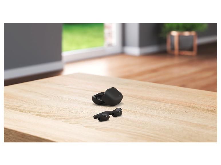 Écouteurs sans fil noirs avec étui de chargement sur une table en bois.