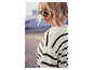Une femme dans un pull rayé portant des lunettes de soleil.