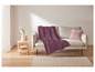 Une couverture violette sur un canapé beige avec un coussin assorti.