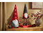 Deux gnomes festifs avec des chapeaux lumineux et un vase de baies rouges sur une surface en bois.