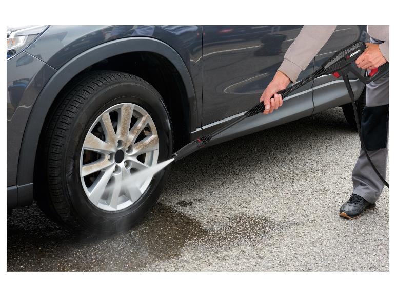 Homme lavant une roue de voiture sale avec un nettoyeur haute pression.
