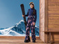 Une fille vêtue de vêtements de ski tient un ski.