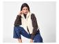 Femme en gilet polaire crème, pull à col roulé marron et jean bleu.