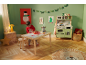 Un enfant joue avec une cuisine et une table en bois dans une pièce décorée pour Noël.